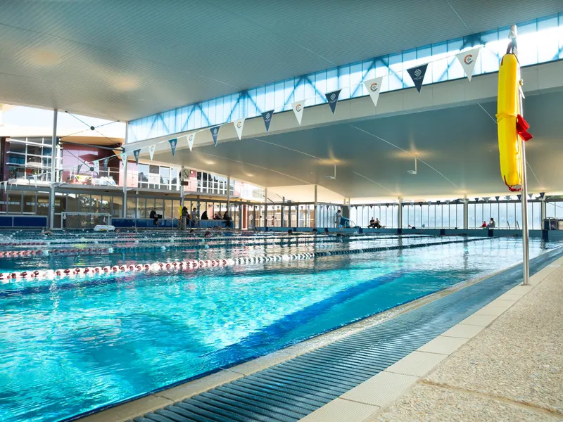 The main indoor pool with lane ropes set and a lifesaving ring on the deck