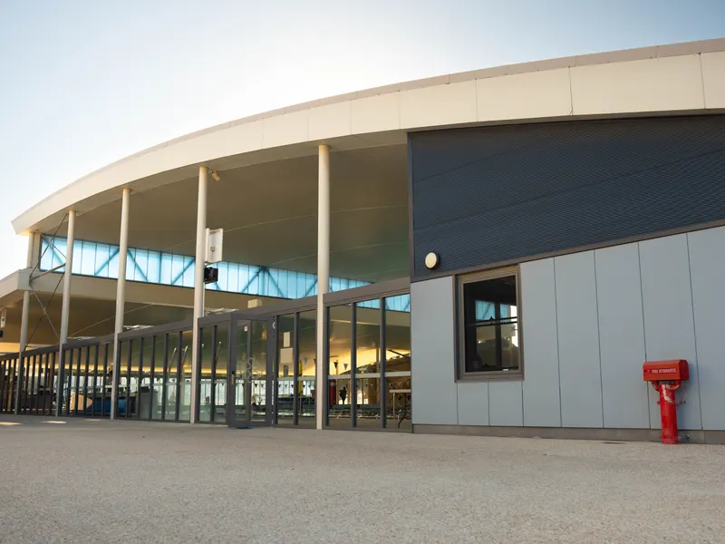 The glazed side elevation of the Jennifer Reilly Aquatic Centre, with the side entrance doors opening onto the paved forecourt