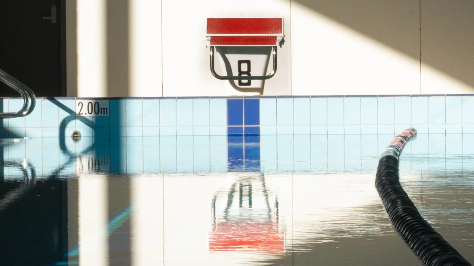 A starting block reflected in the still surface of the pool before a session